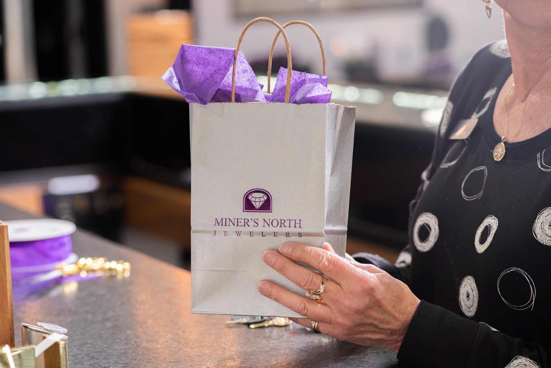 Model Holding a Miner's North Jewelers Gift Bag